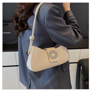 Detail of a beige shoulder bag with a sparkling rhinestone buckle and knotted strap