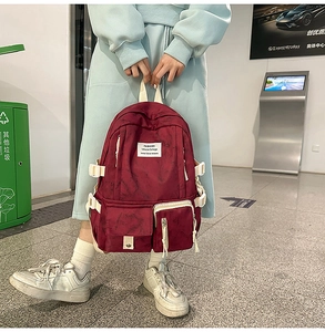 Vue détaillée d'un sac à dos bordeaux avec étiquettes mode et sangles latérales blanches