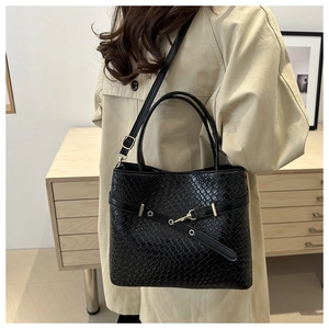 Détail du sac seau noir en cuir embossé avec boucle dorée et bandoulière réglable