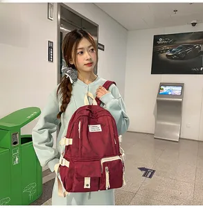 Détail d'un sac à dos tie-dye bordeaux avec sangles blanches porté par un modèle