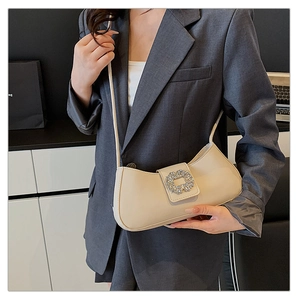 Détail d'un sac à bandoulière crème chic avec boucle en diamant étincelante et lanière en cuir