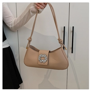 Détail du sac baguette beige avec grande boucle en cristal et bandoulière nouée