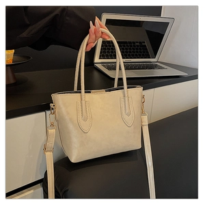 Detail of beige faux leather tote bag with gold hardware and removable shoulder strap