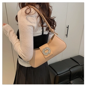 Gros plan d'un sac porté épaule en cuir beige avec boucle en cristal sur modèle