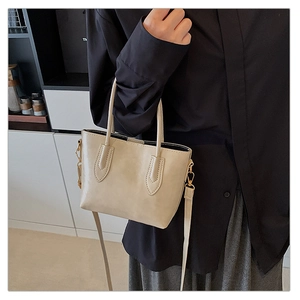 Close-up of cream tote bag with fine stitching, twin handles and adjustable shoulder strap