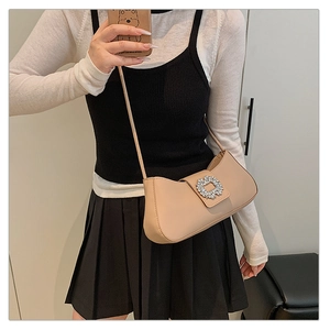 Detail of beige shoulder bag featuring a crystal buckle and sleek leather texture