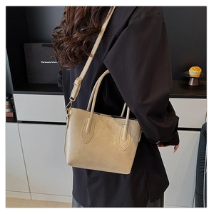 Beige faux leather tote bag with adjustable shoulder strap shown on model's shoulder