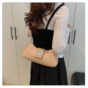 Détail d'un élégant sac baguette beige avec boucle strass porté à l'épaule
