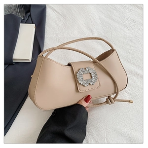 Gros plan d'un sac à bandoulière beige avec une boucle carrée en strass scintillants