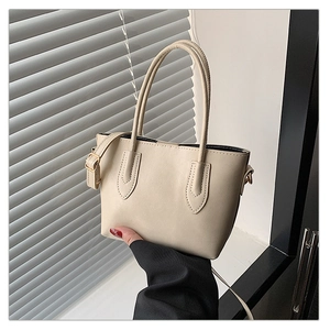 Detail of cream tote bag showing fine PU leather texture and gold buckle shoulder strap