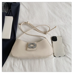 Vue détaillée du sac demi-lune crème avec une boucle de strass carrée luxueuse
