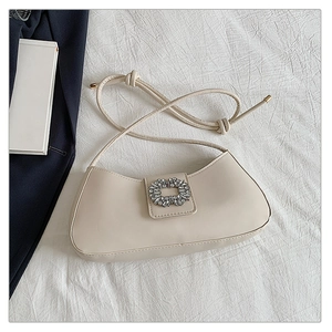 Gros plan du sac à bandoulière beige en demi-lune avec boucle carrée en strass brillants