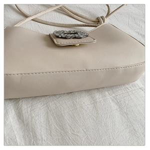 Détail d'un sac d'épaule en cuir beige doté d'une grande boucle en cristal étincelant