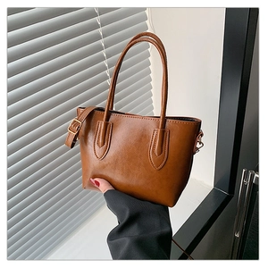 Close-up of caramel brown tote bag showing glossy texture and adjustable shoulder strap