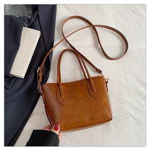 Detail of caramel brown PU leather tote bag with glossy texture and shoulder strap