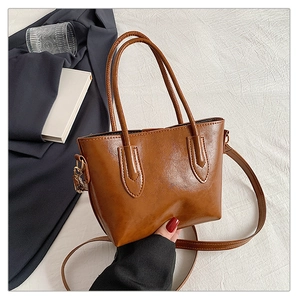 Detailed view of brown PU leather tote bag with dual handles and long shoulder strap