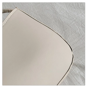 Gros plan d'un sac en cuir beige montrant des coutures précises et une texture lisse