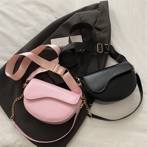 Detail of pink and black leather saddle bags with wide logo straps on a grey blazer