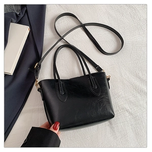 Detail of black faux leather tote bag texture with gold hardware and adjustable strap