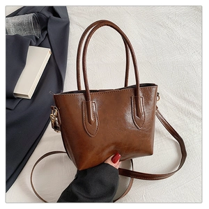 Detailed view of brown faux leather tote bag with metallic D-ring and texture details