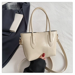 Detail of cream tote bag with litchi texture handle and adjustable shoulder strap