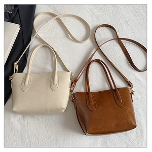 Detail showing minimalist cream and caramel tote bags with dual handles on textured fabric
