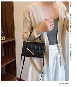 Detail of black quilted shoulder bag with gold metal trim and diamond stitch pattern