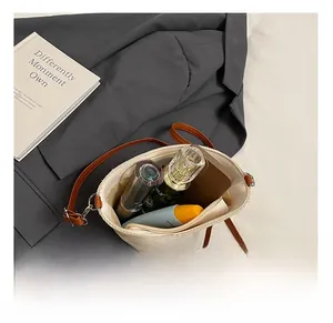 Vue de dessus de l'intérieur du sac tissé beige montrant parfum et articles de voyage