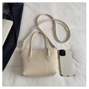 Close-up of cream white tote bag with faux leather texture and adjustable shoulder strap