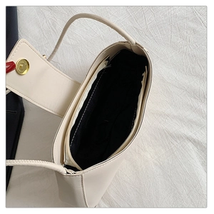 Détail intérieur d'un sac porté épaule beige montrant la doublure noire et boucle dorée