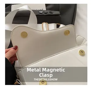 Detail of white saddle bag showing gold magnetic snap closure and wide woven strap