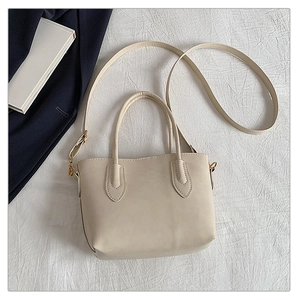 Detail of minimalist cream white tote bag with gold hardware and adjustable strap