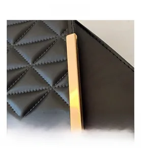 Detailed macro view of black quilted leather texture with gold metal hardware ornament