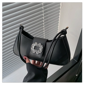 Détail d'un sac à bandoulière en cuir noir avec une boucle en cristal scintillante