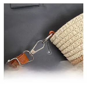 Détail du sac tressé en paille avec fermoir mousqueton argenté et bandoulière cuir