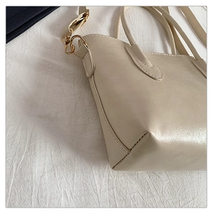 Close-up of beige tote bag showing wrinkled leather texture and golden metal hardware