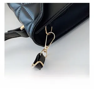 Close-up of golden metal lobster clasp and adjustable leather strap on black quilted bag