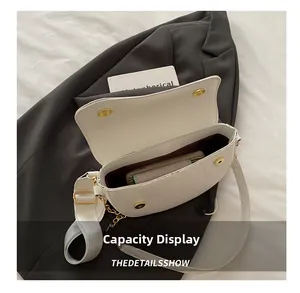 Top-down view of white leather saddle bag interior showing storage space and gold hardware