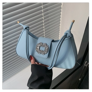 Détail du sac bleu clair avec boucle en cristal emblématique et sangle nouée