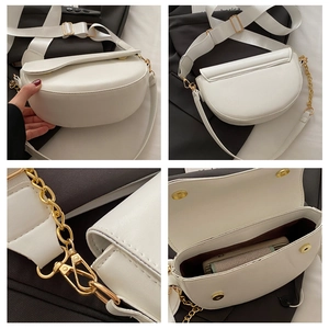 Detail of white saddle bag with wide strap, gold chain, and magnetic buckle closure