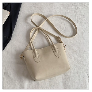 Detail of cream white faux leather tote bag with gold hardware and adjustable strap