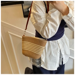 Détail de la sacoche en paille tressée avec rayures et bandoulière en cuir marron