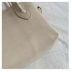 Detailed close-up of beige pleated PU leather texture and gold metal D-ring attachment