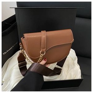 Detail of brown saddle bag with gold metal buckle and woven strap on luxury background