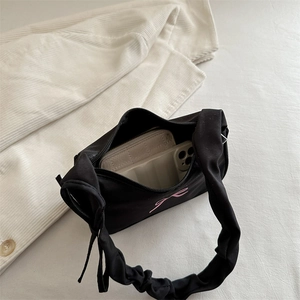 Black shoulder bag with pink bow print and scrunchie strap shown with phone and wallet