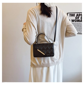 Detail of black quilted shoulder bag featuring gold metal trim and diamond stitching