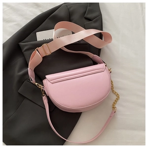 Pink crescent saddle bag with wide fabric strap and gold chain on gray blazer