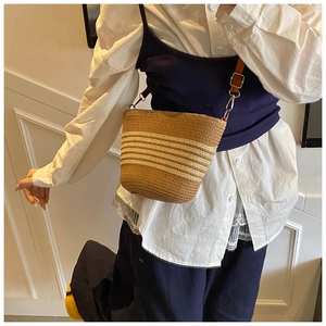 Dettaglio della borsa tote a righe in paglia con tracolla in pelle marrone e trama intrecciata