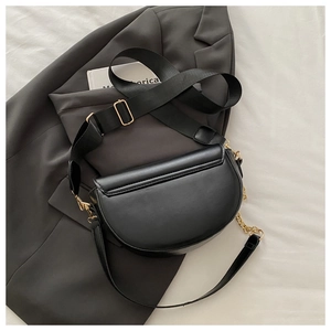 Detail view of black half-moon crossbody bag with golden chain and adjustable strap