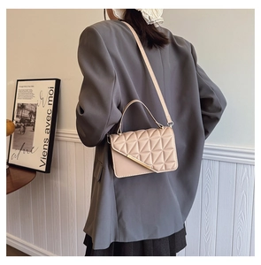 Detail of beige quilted crossbody bag with triangle stitching and gold metal fastener